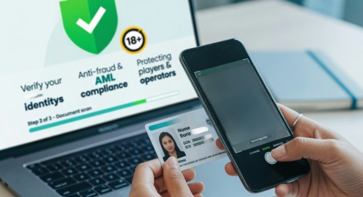 Hands scan an ID with a smartphone in front of a laptop showing an